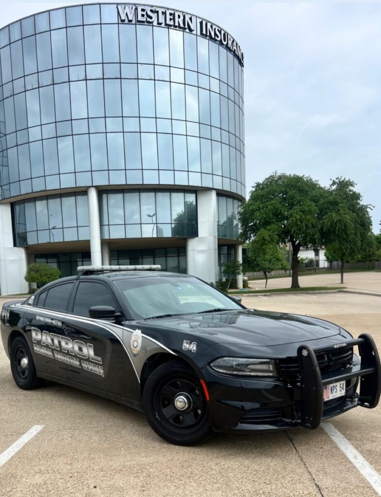 A black police patrol car parked in front of a glass office building labeled "Western Insurance.